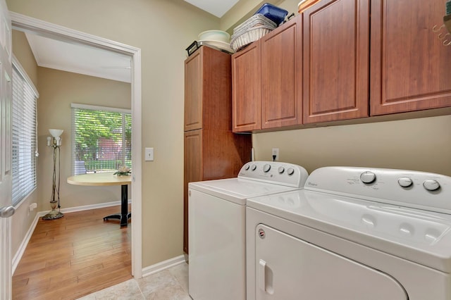 clothes washing area with light wood-style floors, baseboards, cabinet space, and independent washer and dryer