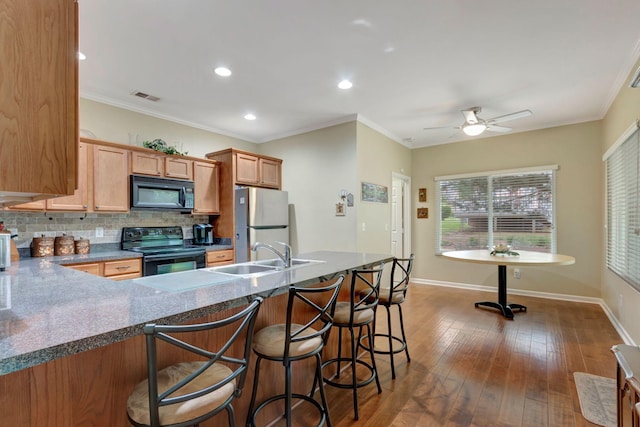 kitchen with a sink, baseboards, decorative backsplash, visible vents, and black appliances