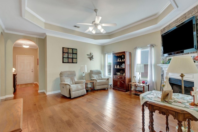 bedroom featuring arched walkways, a tray ceiling, visible vents, and light wood-type flooring