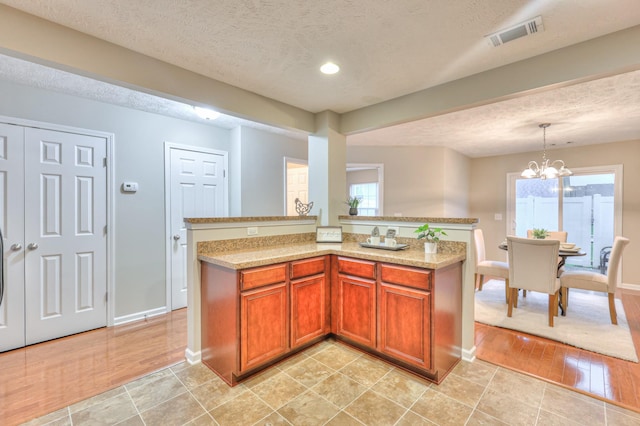 2039 Caladonia Way, Smyrna, TN 37167 - kitchen featuring visible vents, an inviting chandelier, baseboards, a textured ceiling, and brown cabinets