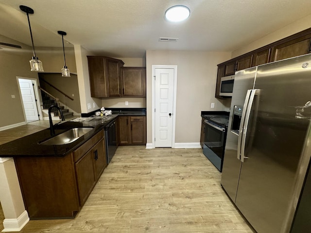 kitchen featuring visible vents, light wood-style floors, baseboards, a sink, and stainless steel appliances