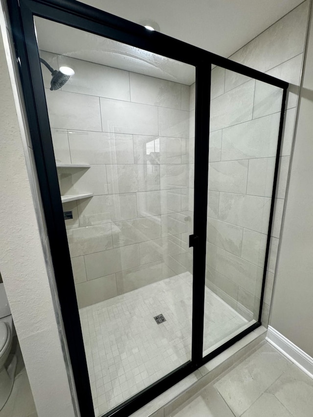 bathroom featuring baseboards, a stall shower, toilet, and marble finish floor