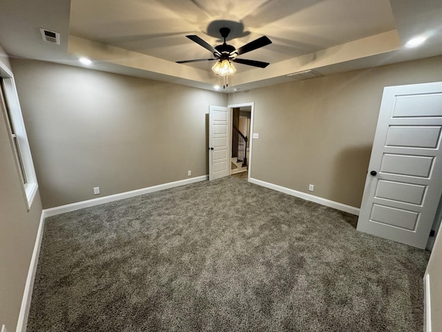 unfurnished bedroom featuring a raised ceiling, baseboards, and carpet floors