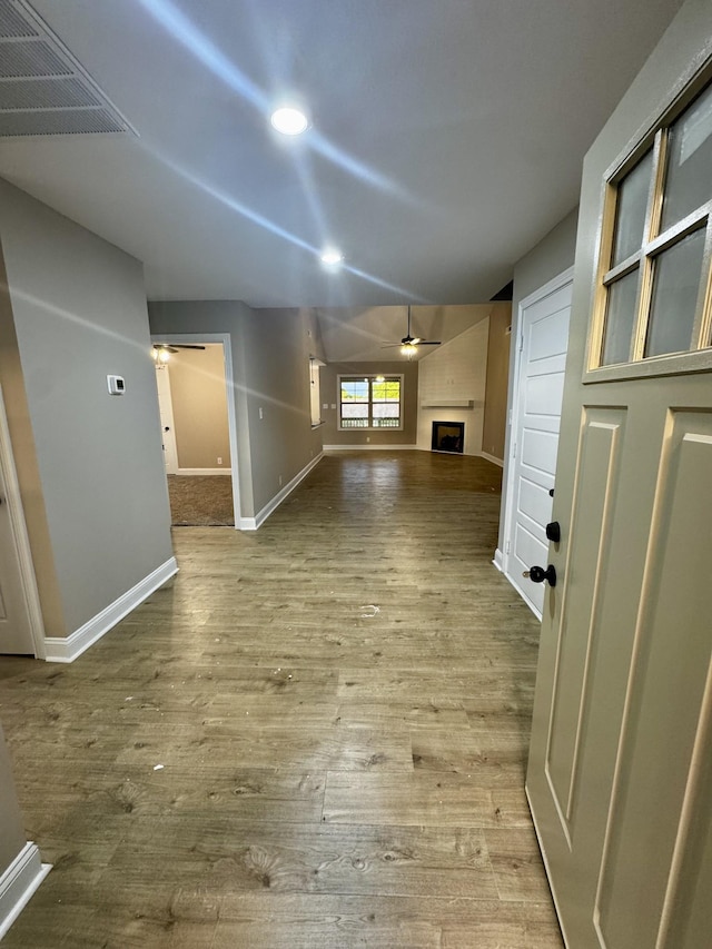 unfurnished living room featuring a ceiling fan, baseboards, visible vents, and a fireplace