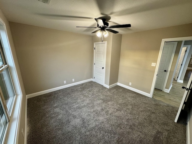 unfurnished bedroom featuring dark carpet, baseboards, and ceiling fan
