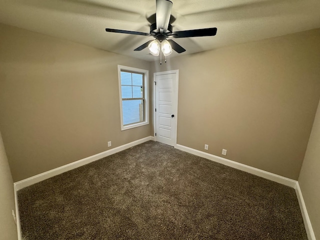 unfurnished room with a ceiling fan, baseboards, and dark carpet