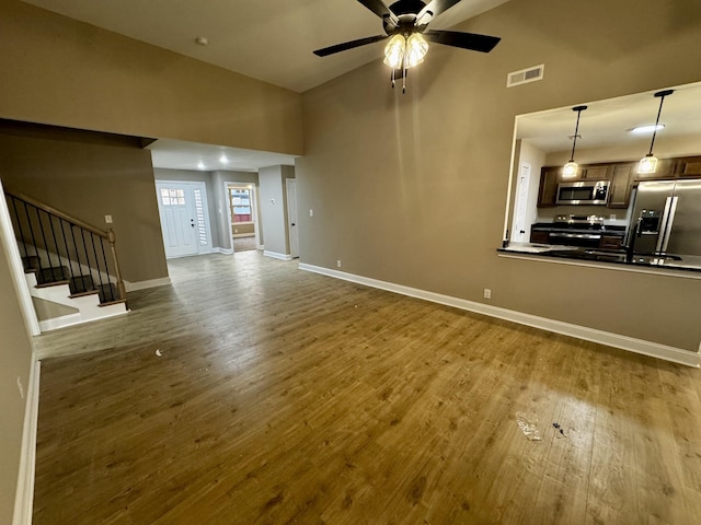 unfurnished living room with dark wood finished floors, stairs, a ceiling fan, baseboards, and visible vents