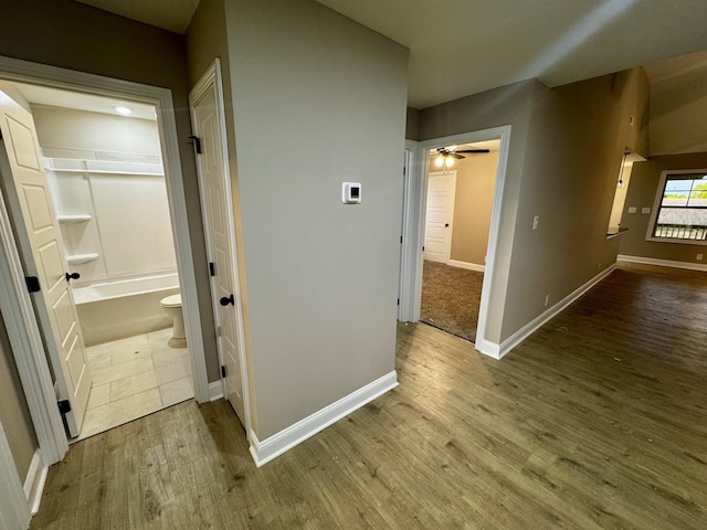 corridor with baseboards and wood finished floors