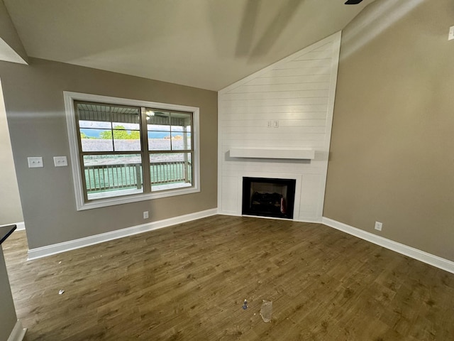 unfurnished living room featuring a fireplace, baseboards, lofted ceiling, and dark wood-type flooring