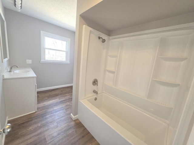 full bath with baseboards, a textured ceiling, wood finished floors, and vanity