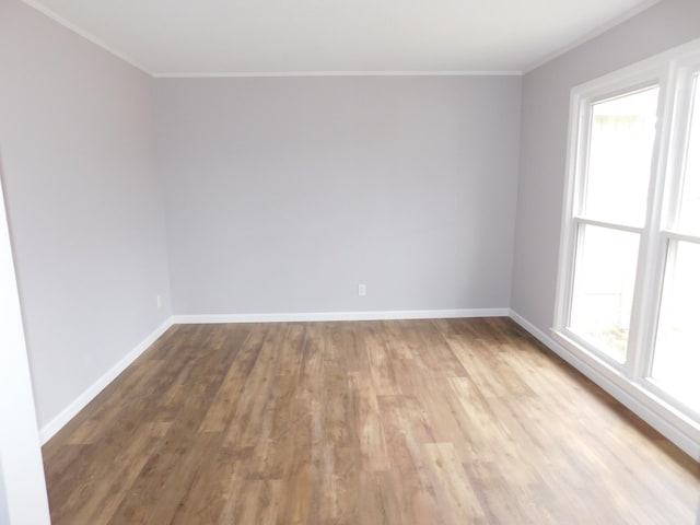 empty room with ornamental molding, plenty of natural light, and wood finished floors