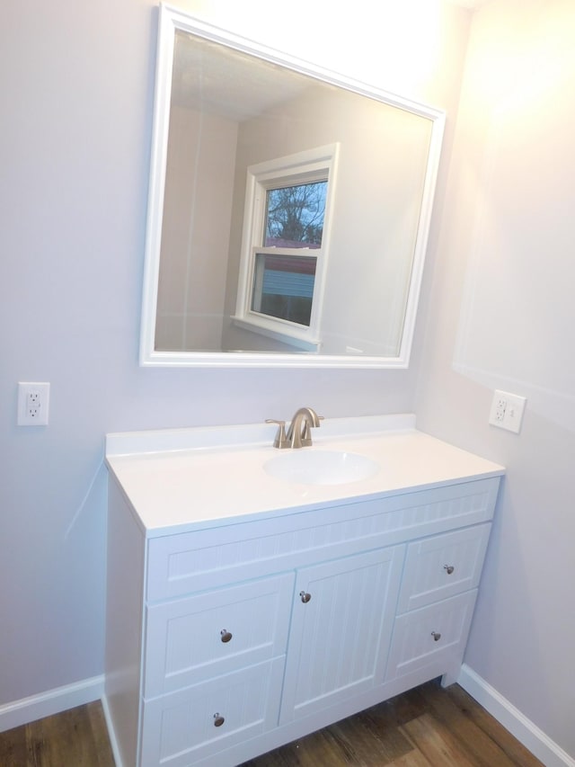 bathroom with baseboards, wood finished floors, and vanity