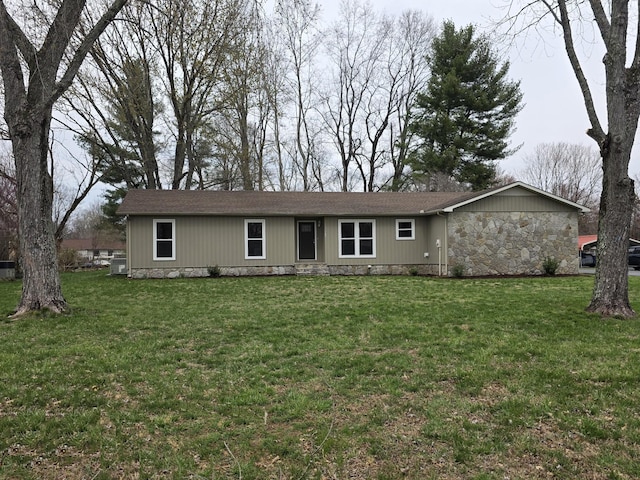 rear view of house featuring a lawn, a shingled roof, and stone siding