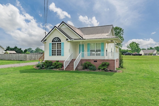 view of front of property with covered porch, driveway, metal roof, fence, and a front lawn