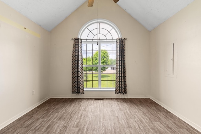 empty room featuring a ceiling fan, baseboards, wood finished floors, and lofted ceiling