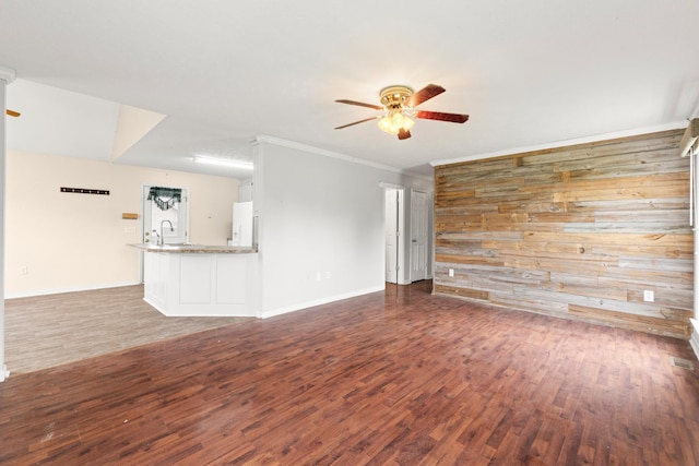unfurnished living room featuring baseboards, ornamental molding, ceiling fan, and wood finished floors