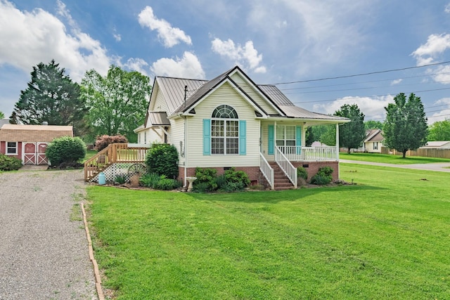 view of front of property featuring covered porch, metal roof, an outbuilding, a front lawn, and stairs