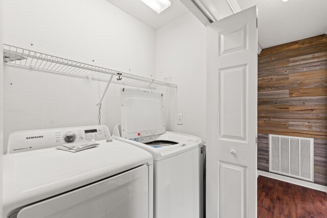 laundry room with wood walls, visible vents, washing machine and dryer, and laundry area