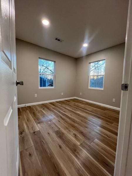 unfurnished room featuring baseboards, plenty of natural light, and wood finished floors