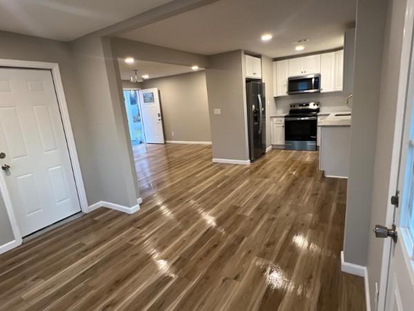 interior space featuring white cabinets, light countertops, stainless steel appliances, open floor plan, and baseboards