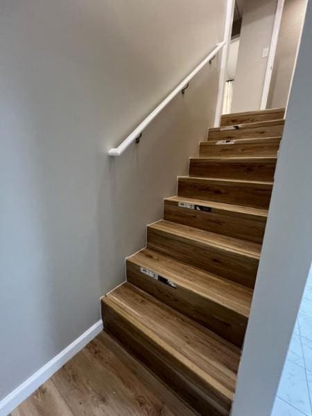 staircase with baseboards and wood finished floors