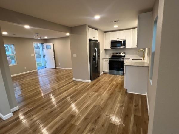 kitchen with a sink, dark wood-style flooring, appliances with stainless steel finishes, and open floor plan