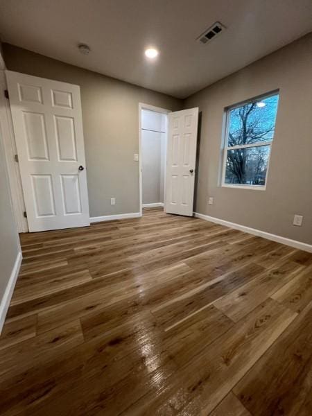 unfurnished bedroom with baseboards, recessed lighting, wood finished floors, and visible vents