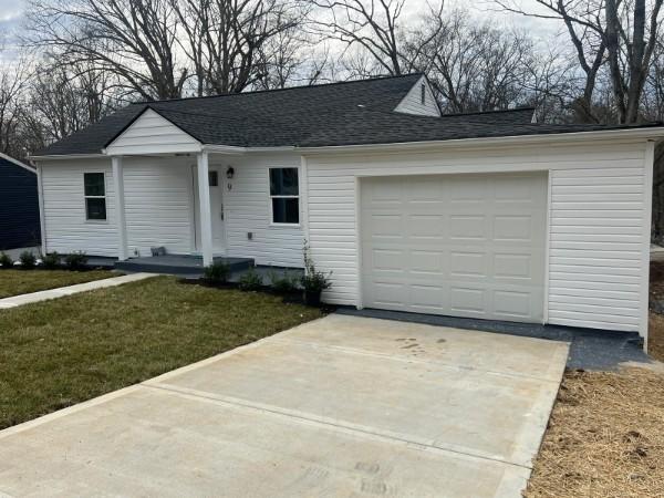 single story home featuring concrete driveway, an attached garage, roof with shingles, and a front lawn