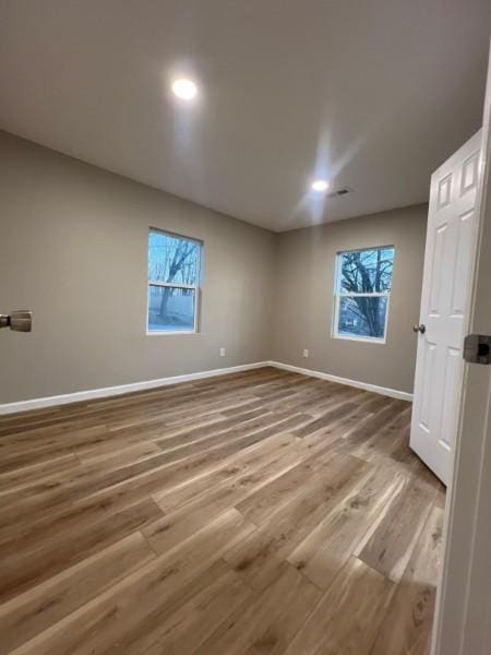 spare room with baseboards, plenty of natural light, and wood finished floors