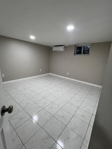 finished below grade area featuring an AC wall unit, recessed lighting, baseboards, and marble finish floor