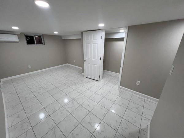 finished basement with recessed lighting, baseboards, marble finish floor, and a wall mounted air conditioner