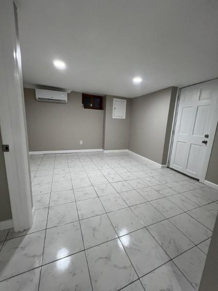 finished basement with recessed lighting, baseboards, and a wall mounted air conditioner