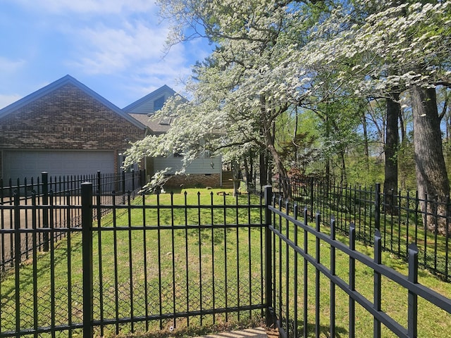 view of yard featuring driveway, fence private yard, and a garage