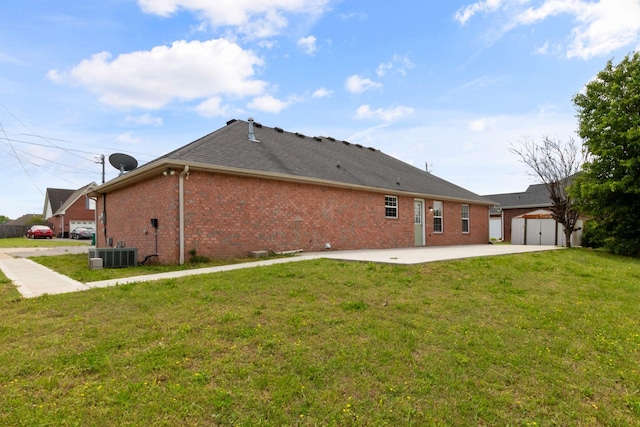 rear view of property with an outdoor structure, a patio, a shed, brick siding, and a yard