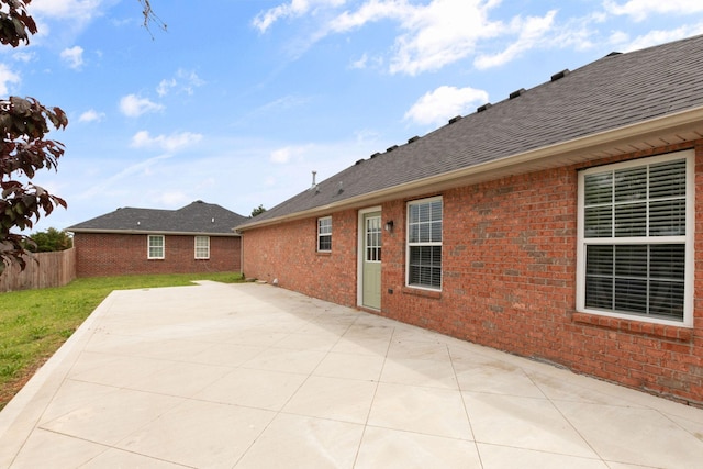 rear view of property with a lawn, brick siding, fence, and a shingled roof