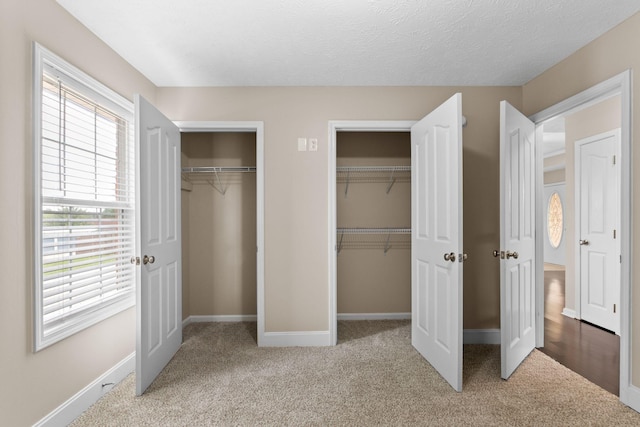 unfurnished bedroom featuring carpet floors, multiple closets, and baseboards