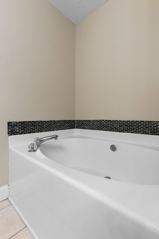 full bath featuring a bath, a textured ceiling, and tile patterned flooring