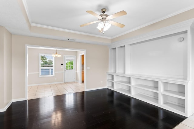 unfurnished living room featuring baseboards, ceiling fan with notable chandelier, crown molding, and wood finished floors