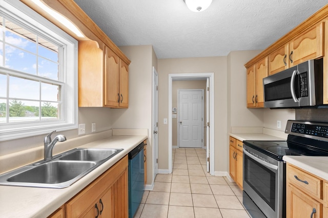 kitchen with light tile patterned flooring, a sink, light brown cabinets, light countertops, and stainless steel appliances
