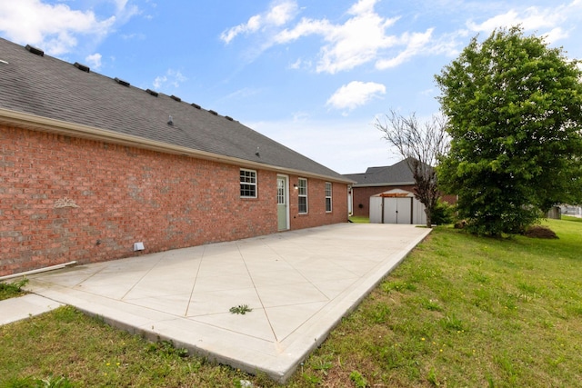 back of property featuring brick siding, a shed, an outbuilding, a patio, and a yard