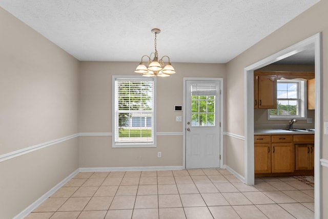 doorway to outside with an inviting chandelier, a sink, baseboards, and a textured ceiling