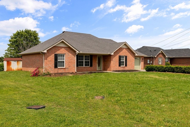 ranch-style house with a storage shed, an outdoor structure, a front lawn, and brick siding