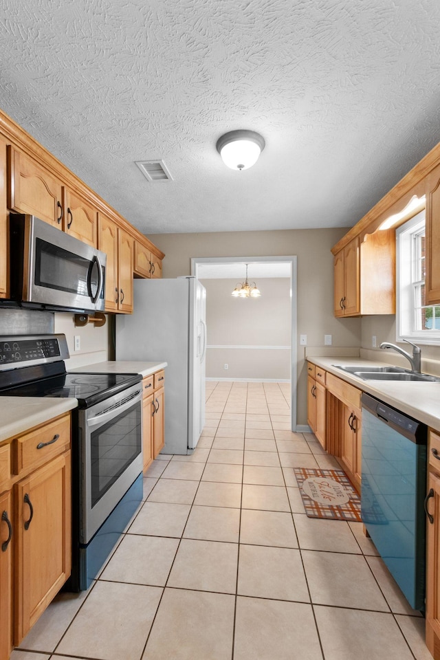 kitchen featuring visible vents, appliances with stainless steel finishes, a sink, light countertops, and a notable chandelier
