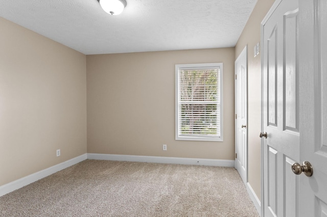 carpeted empty room featuring baseboards and a textured ceiling