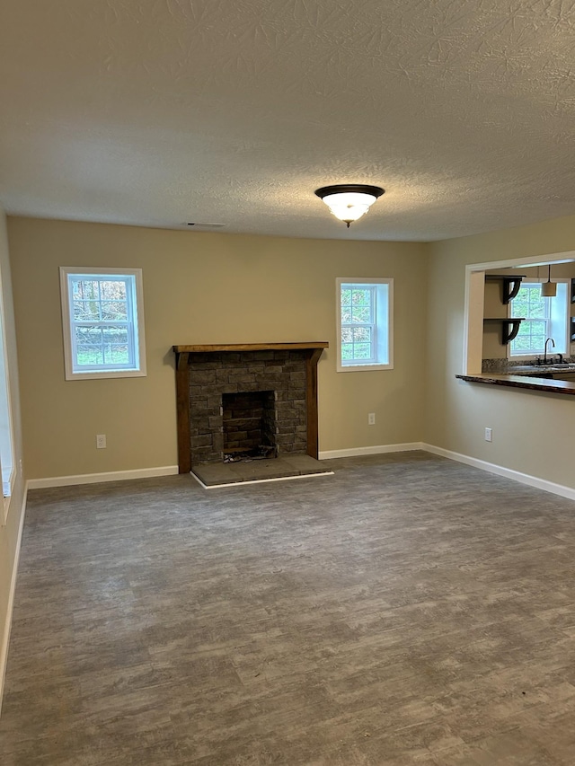 unfurnished living room featuring baseboards, dark wood finished floors, and a textured ceiling