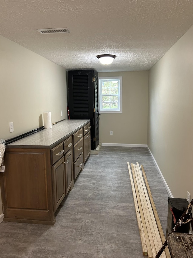 interior space with a textured ceiling, baseboards, visible vents, and wood finished floors