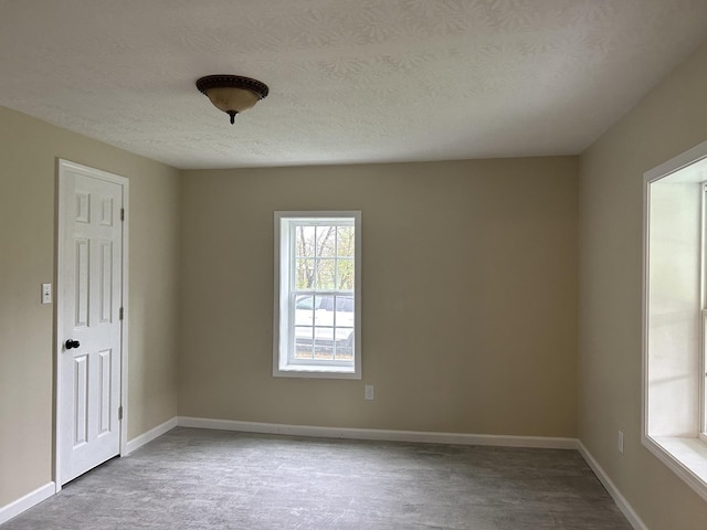 unfurnished room featuring baseboards, a textured ceiling, and wood finished floors