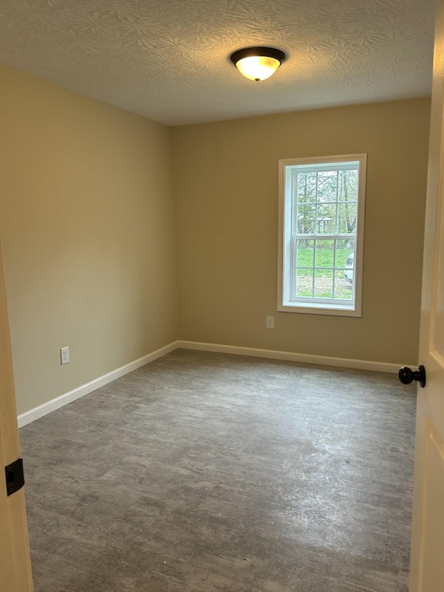 empty room with baseboards and a textured ceiling