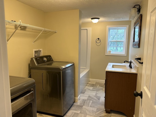 washroom featuring separate washer and dryer, a sink, baseboards, and laundry area