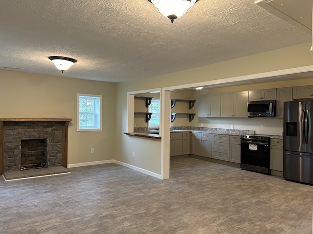 kitchen with gray cabinets, a textured ceiling, a fireplace, baseboards, and stainless steel appliances